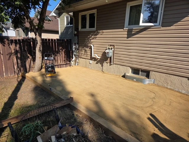 Compacted sand and gravel base with edge forms ready for a backyard patio pour, Regina SK